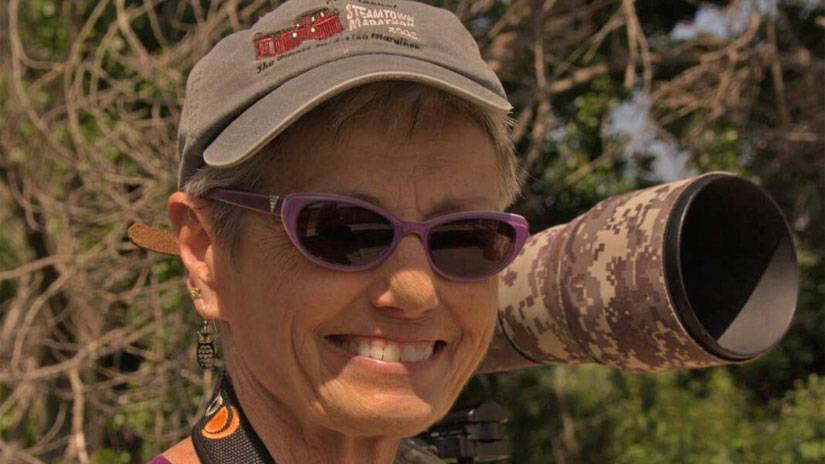 San Fernando Valley Audubon Society,Pat Bates, smiling with her teleschope at her right ear.