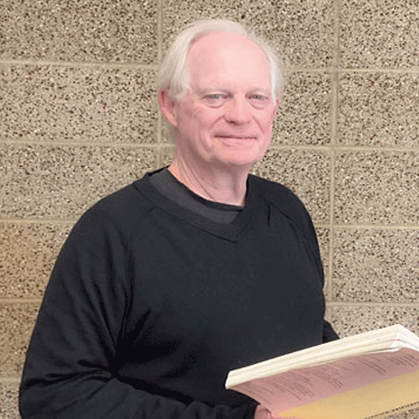 Instructor Robert Foxx looking at the camera, holding a book.
