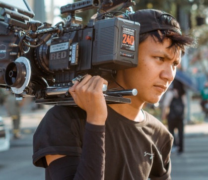 Student holding film camera over shoulder