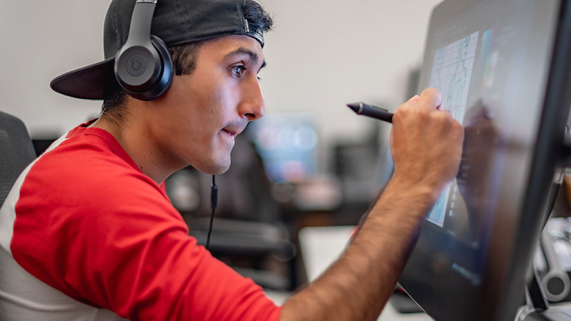 Photo is of student using a computer creating with a stylus pen