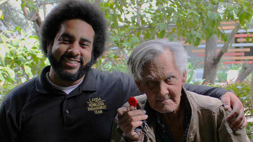 Client Larry showing the key to his permanent home that LAHSA Outreach member Malik helped him find.